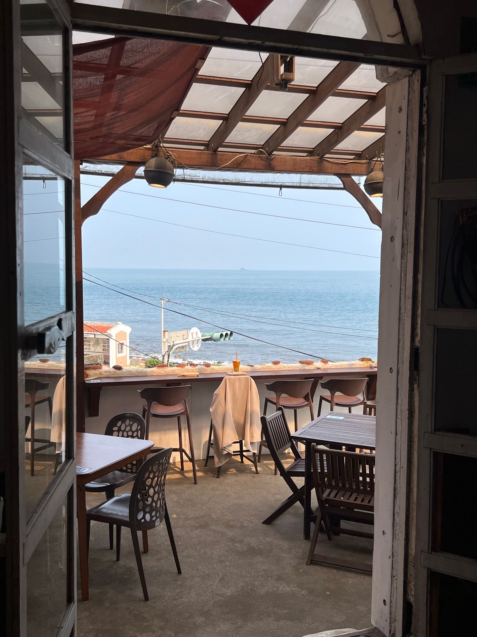 扉の向こうに青い海が広がるカフェのテラス